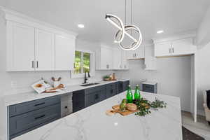 Dual tone kitchen with two tone color scheme, light stone countertops, hanging lights, and wood finished floors