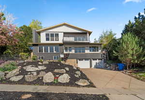 View of front of home featuring a balcony, driveway, and a garage