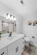 Full bathroom with vanity, a marble finish shower, and dark wood-type flooring