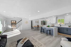 Living room with a textured ceiling, light wood-style flooring, and recessed lighting