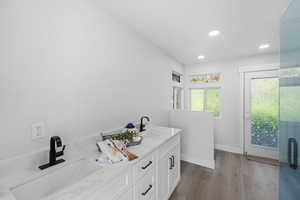 Full bathroom featuring double vanity, dark wood-style floors, and recessed lighting