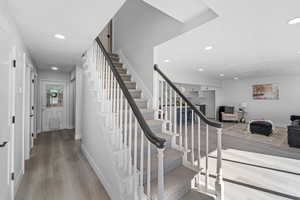 Stairs featuring wood finished floors and recessed lighting