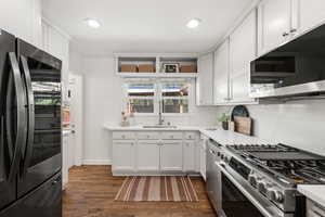Kitchen with stainless steel appliances, white cabinetry, dark wood-style flooring, recessed lighting, and light stone countertops
