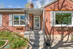 Doorway to property featuring brick siding and a chimney