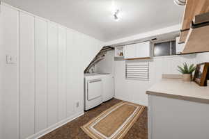 Laundry area with washing machine and dryer, wooden walls, and cabinet space
