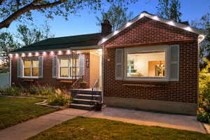View of front of home with a lawn, brick siding, and a chimney