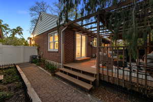 Rear view of house featuring brick siding and a wooden deck