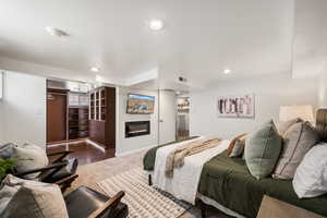 Carpeted bedroom featuring a glass covered fireplace, a closet, and recessed lighting