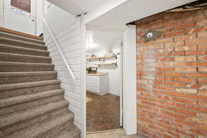 Staircase featuring wood finished floors and brick wall