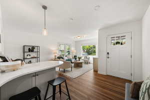 Kitchen with open floor plan, a breakfast bar, dark wood-type flooring, pendant lighting, and gray cabinets
