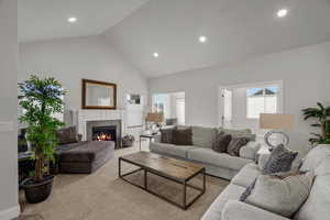 Living area featuring a tiled fireplace, carpet, a high ceiling, and recessed lighting