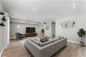 Living room with light wood-type flooring and recessed lighting