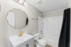 Bathroom with vanity, a textured ceiling, shower / tub combo with curtain, and a textured wall