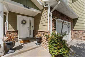Entrance to property featuring stone siding, a garage, and driveway