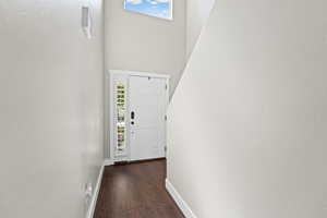 Doorway with a textured wall, wood finished floors, and a high ceiling