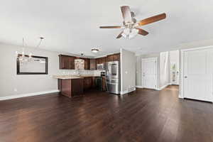 Kitchen with stainless steel appliances, dark wood finish cabinetry, hanging lights, a ceiling fan, and dark wood-type flooring