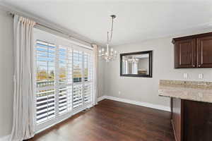 Unfurnished dining area featuring suspended lighting and dark wood-style floors