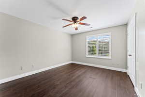 Empty room with dark wood-style floors and a ceiling fan