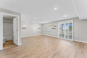 Basement with a textured ceiling, light wood-style flooring, and recessed lighting