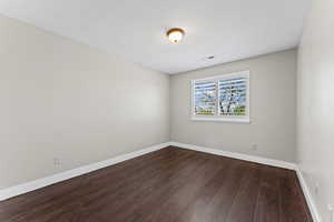 Spare room featuring dark wood finished floors