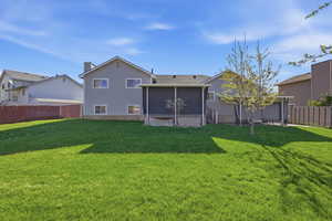 Rear view of house featuring a fenced backyard, a wooden deck, a sunroom, and a chimney