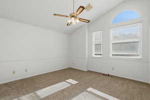Empty room with lofted ceiling, ceiling fan, and carpet