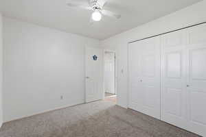 Unfurnished bedroom with carpet, a closet, and a ceiling fan