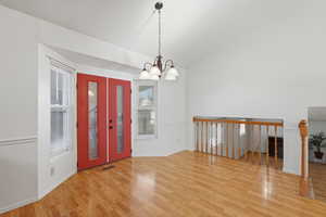 Foyer entrance with lofted ceiling, light wood-style flooring, and a chandelier