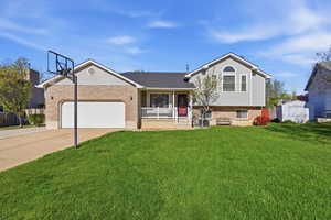 Split level home with covered porch, driveway, a front lawn, and an attached garage