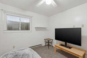 Carpeted bedroom featuring a baseboard heating unit and ceiling fan