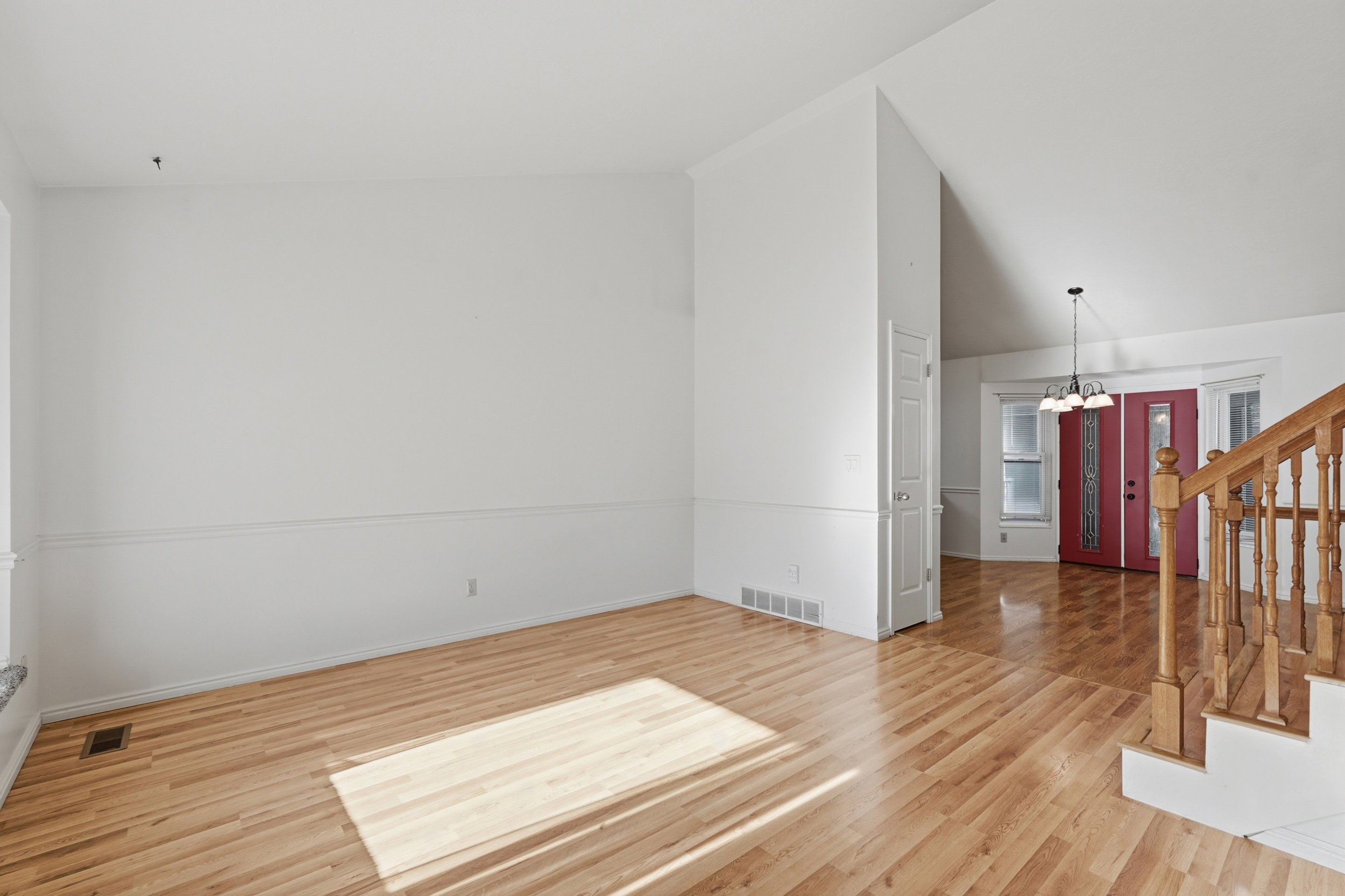 Spare room featuring vaulted ceiling, light wood-type flooring, and hanging lights