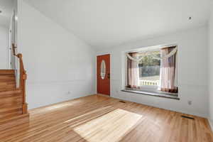 Foyer with vaulted ceiling and light wood finished floors