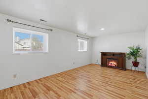 Unfurnished living room with light wood-style floors and a glass covered fireplace