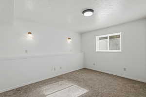 Unfurnished room featuring carpet and a textured ceiling