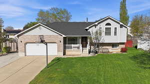 Split level home with concrete driveway, a front yard, covered porch, and brick siding
