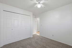 Unfurnished bedroom featuring a closet, light carpet, and a ceiling fan