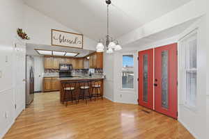Kitchen with wood finish cabinetry, hanging lights, a kitchen bar, a peninsula, and tasteful backsplash