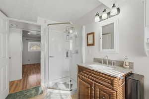 Bathroom featuring vanity, a stall shower, a textured ceiling, and light wood-style flooring