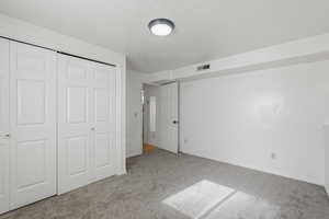 Unfurnished bedroom with a closet, light colored carpet, and a textured ceiling