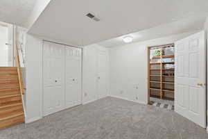 Unfurnished bedroom with a textured ceiling, carpet, and two closets