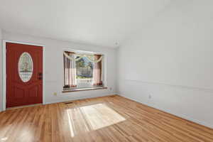 Foyer entrance featuring vaulted ceiling and light wood-type flooring