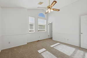 Carpeted empty room with ceiling fan and lofted ceiling