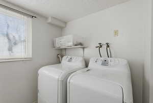 Laundry room with independent washer and dryer and a textured ceiling