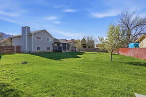 Fenced backyard featuring a wooden deck and a sunroom