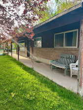 View of side of property featuring a lawn and brick siding