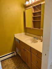 Bathroom featuring a baseboard radiator, vanity, and brick patterned floors