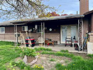Back of property featuring brick siding, a chimney, and a patio