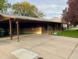 Rear view of property featuring brick siding, driveway, an attached carport, and a yard