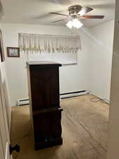 Spare room featuring light colored carpet, a ceiling fan, and a baseboard heating unit