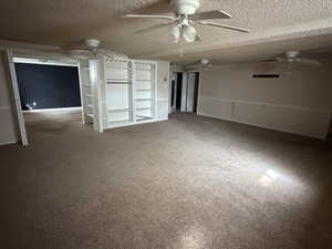 Unfurnished bedroom featuring carpet, a textured ceiling, and a ceiling fan
